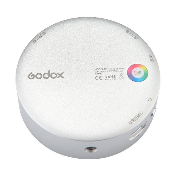 The Godox R1 is a round, silver device with labelled buttons, ports, an RGB light indicator and printed text with certification markings.