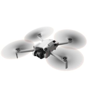 DJI Mini 4 Pro -lennokki, valkoinen nelikopteri, jossa on neljä potkuria ja asennettu kamera, näkyy kesken lennon valkoista taustaa vasten.