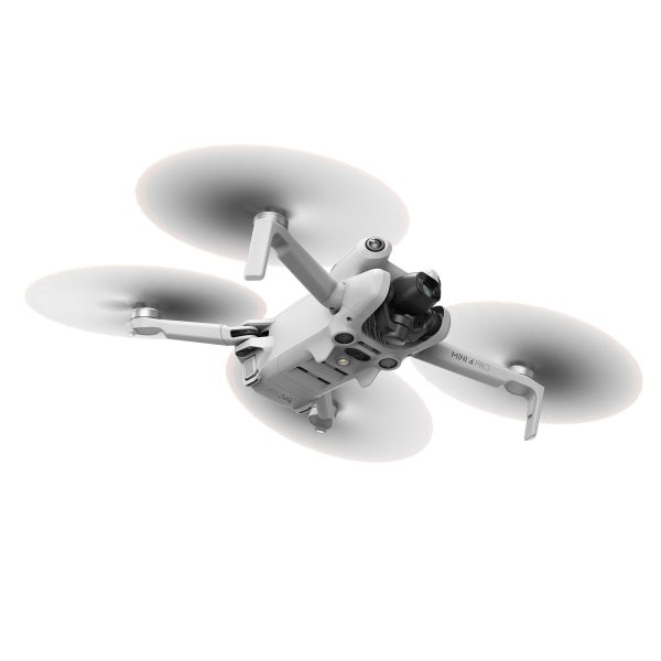 DJI Mini 4 Pro -lennokki, valkoinen nelikopteri, jossa on pyörivät potkurit, näkyy kesken lennon valkoista taustaa vasten. Etupuolen alapuolella on sen kamera ja anturit.