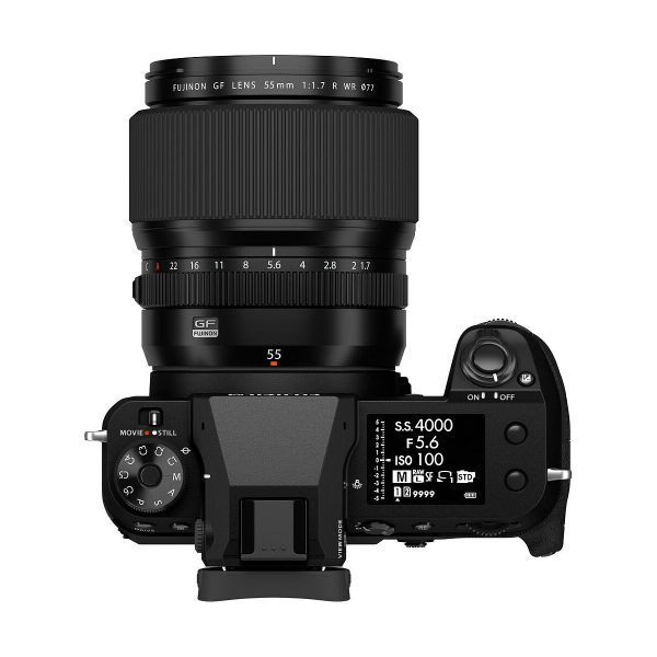 Top view of a black Fujifilm camera with a Fujinon GF 55mm f/1.7 R WR lens attached, with control dials, buttons and a digital display showing the camera settings.
