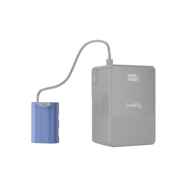 Harmaa SmallRig 4264 USB-C ladattava kamera-akku LP-E6NH on yhdistetty siniseen akkuun lyhyellä kaapelilla. Akun digitaalinen näyttö näyttää 100 %, mikä tarkoittaa, että akku on ladattu täyteen.