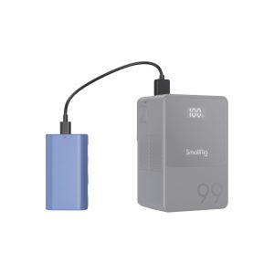 The blue laptop is connected with a black cable to a grey SmallRig 4331 USB-C rechargeable camera battery NP-F550 with "99" engraved on the bottom. The digital display of the device shows "100L".
