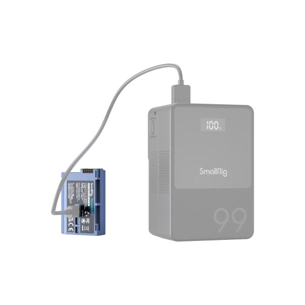 Sininen SmallRig 4332 USB-C ladattava kamera-akku EN-EL15c on kytketty kaapelilla harmaaseen virtalähteeseen, jonka näytössä lukee "100", mikä tarkoittaa täyttä latausta. Molemmat laitteet on asetettu valkoista taustaa vasten.