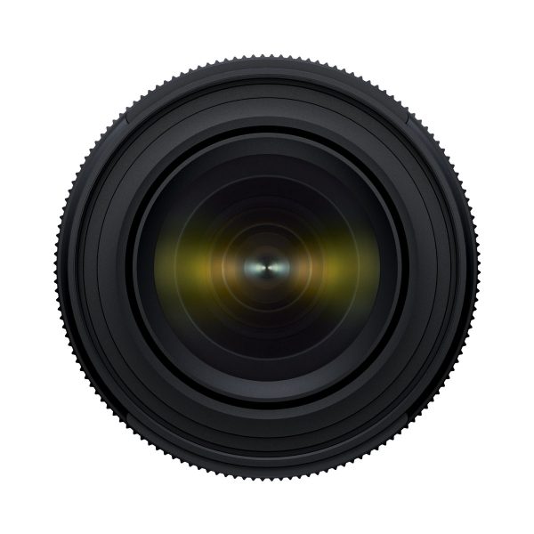 Tamron_17-50_f4_004 Lähikuva Tamron 17-50mm F/4 Di III VXD -objektiivista Sony E:lle, jossa objektiivi on suunnattu eteenpäin, ja siinä on näkyvät samankeskiset renkaat ja heijastetut lasielementit valkoista taustaa vasten.