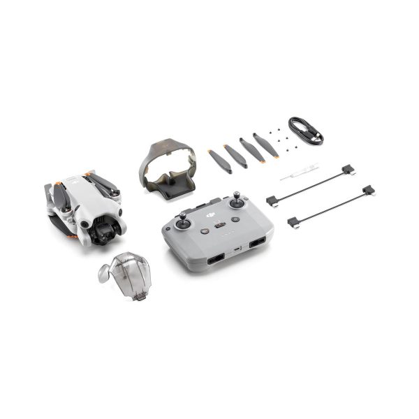 The DJI Mini 4 Pro drone kit contains the folded drone, remote control, battery charger, propellers, cables, screws and propeller guards neatly arranged on a white background.