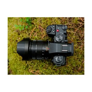Panasonic Lumix G9 II -järjestelmäkamera suurella objektiivilla lepää vihreällä sammaloituneella maalla ylhäältä katsottuna.