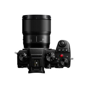 Top-down view of a black digital camera with various controls and Panasonic Lumix S 35mm f/1.8 lens, on a plain white background.