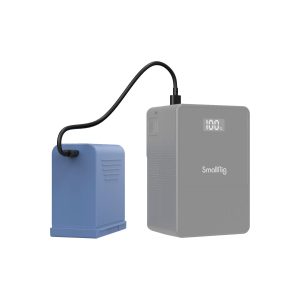 The blue battery is connected with a black cable to a grey SmallRig 4267 USB-C rechargeable camera battery NP-F970 with a digital display showing 100 % on a white background.