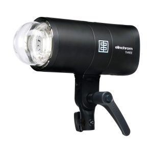 Elinchrom THREE, musta studiostroboskooppivalaisin, jossa on lasinen salamaputki ja säädettävä kahva kannattimella, näkyy valkoista taustaa vasten.
