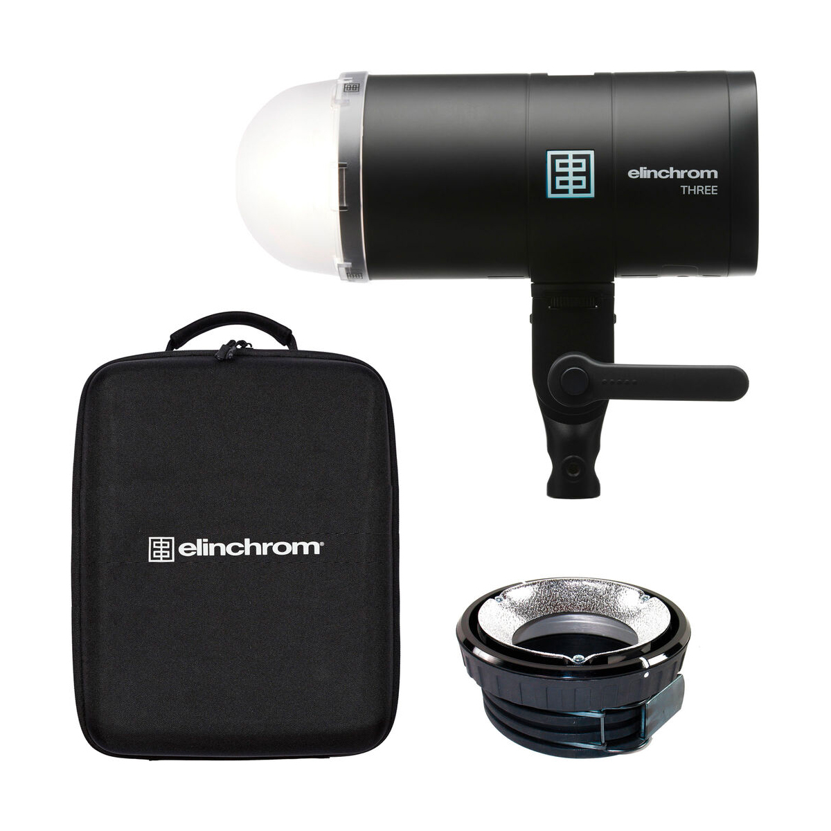 Elinchrom THREE -studiovalaisin mustana, kuvassa kupolidiffuusori, pyöreä hopeinen heijastin ja yhteensopiva musta kantolaukku valkoisella pohjalla.