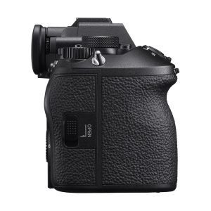Side view of a black Sony A9 III system camera with textured grip, viewfinder, control buttons and OPEN-marked compartment, isolated on a white background.