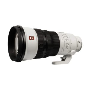 Sony FE 300mm f/2.8 GM OSS -objektiivi on suuri valkoinen teleobjektiivi, jossa on musta kuminen kahva, säätökytkimet, jalustakiinnitys ja G-logo, joka symboloi sen korkealaatuisuutta.