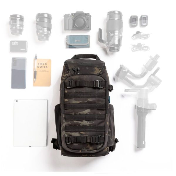 Tenba Axis V2 16L MultiCammusta -reppu näkyy valkoisella taustalla kameroiden, objektiivien, kannettavan tietokoneen, puhelimen, tabletin ja erilaisten kameratarvikkeiden ympäröimänä.