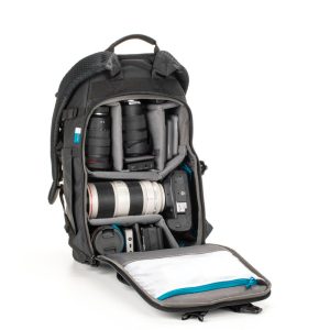 Tenba Axis v2 20L Backpack MultiCammusta -kamerareppu mustana näkyy päälokero auki, jossa on järjestetty kameravarustus - objektiivit, kameran runko, salama ja tarvikkeet pehmustetuissa osissa - ja vetoketjullinen tasku etuläpän päällä.