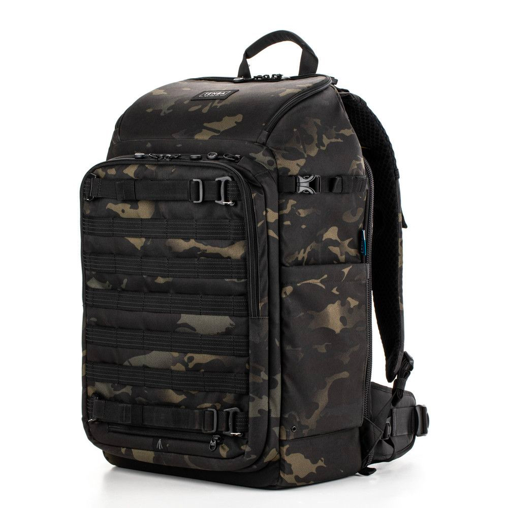 Tenba Axis v2 32L Backpack MultiCam -kamerareppu sisältää mustan ja tummanvihreän maastokuvion, useita vetoketjulokeroita, säädettävät hihnat ja yläkahvan, kuvassa valkoisella pohjalla.