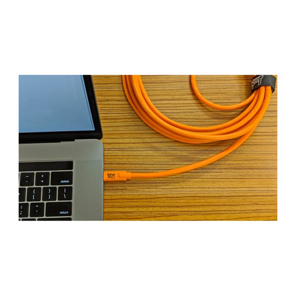 The Tether Tools TetherPro USB-C-2.0 Micro-B 5-pin cable, twisted and secured with Velcro, is partially visible next to the laptop on the wooden surface.