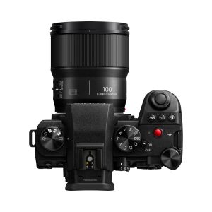 Top view of a black Panasonic digital camera with a Panasonic Lumix S 100mm F/2.8 macro lens attached, showing the controls, buttons and on/off switch on the right.