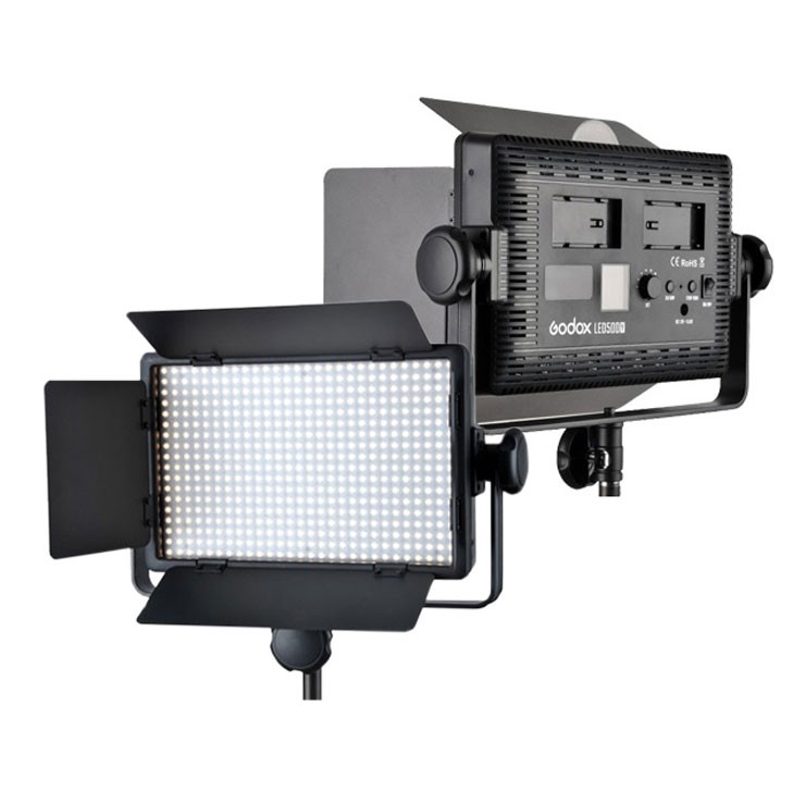 The Godox LED 500Y Tungsten Barndoor is a professional LED panel luminaire on a stand with illuminated front panels and rear power controls with battery compartments.