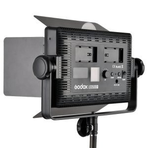 1448269121_407 The Godox LED 500Y Tungsten video light panel with adjustable barn doors, control buttons and two battery compartments is mounted on a light stand and viewed from the rear.