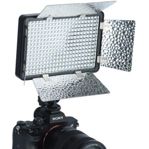 Sony-kamera, joka on varustettu Godox Led LF308D -paneelilla, jossa on kaksi osittain auki olevaa heijastavaa lato-ovea valon suuntaamiseksi. Paneelin pinta on peitetty lukuisilla pienillä LED-lamppuilla.