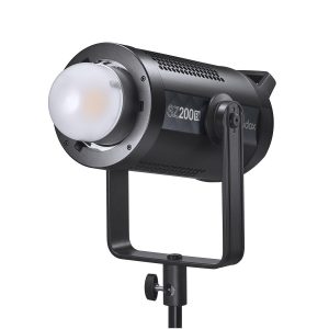 Godox SZ200Bi zoomattava kaksivärinen LED-videovalaisin (LED-valo), musta, pyöristetyllä diffuusorilla, asennettu säädettävään jalustaan, hieman vasemmalle kallistettuna valkoista taustaa vasten.
