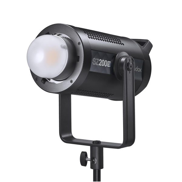 Godox SZ200Bi zoomattava kaksivärinen LED-videovalaisin (LED-valo), musta, pyöristetyllä diffuusorilla, asennettu säädettävään jalustaan, hieman vasemmalle kallistettuna valkoista taustaa vasten.