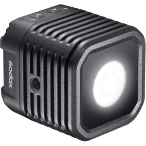 Godox WL4B Waterproof LED-valaisin on kompakti, musta, neliön muotoinen LED, jossa on kirkas pyöreä keskus, lämpöä haihduttavat kyljet ja ohjauspainikkeet yläosassa.
