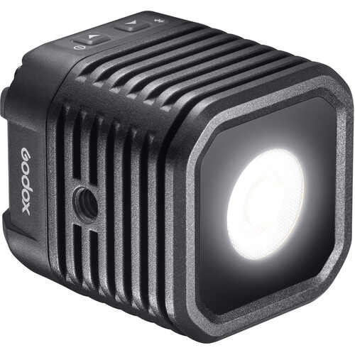 Godox WL4B Waterproof LED-valaisin on kompakti, musta, neliön muotoinen LED, jossa on kirkas pyöreä keskus, lämpöä haihduttavat kyljet ja ohjauspainikkeet yläosassa.