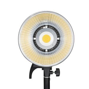 Godox LED SL100D Daylight on pyöreä LED-valaisin, jossa on keskittyvät keltaiset ja hopeiset renkaat ja joka on asennettu mustaan säädettävään jalustaan. Kuvassa edestä valkoista taustaa vasten.