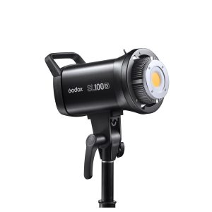 The Godox SL100Bi LED Video Light Two Light Kit, black, is shown mounted diagonally on a tripod. It features a handle, a circular front beam area and control knobs for easy control.
