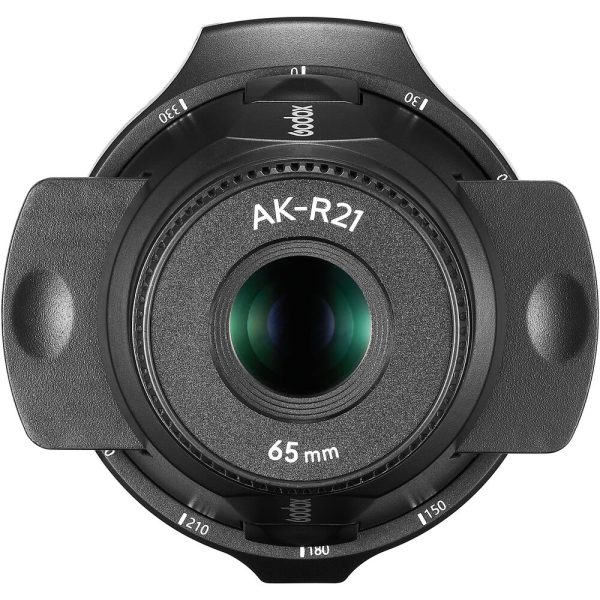 Close-up of the projector attachment of the Godox AK-R21 flashlight with 65 mm lens with black cover and white markings, taken from above to highlight the glass element and surrounding details.