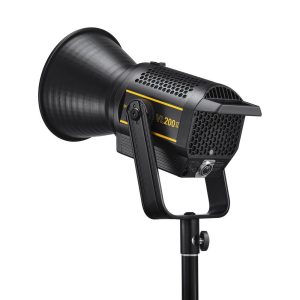 The black and yellow Godox VL200II LED video light is mounted on a tripod when viewed from the side, with a large reflector and visible ventilation grilles.