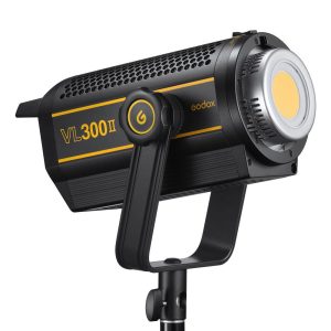 The black and yellow Godox VL300II LED video light is mounted on a tripod, with a power button and large cooling vents in the body.