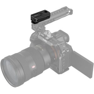 The compact black SmallRig 3902 wireless remote control is attached to the top handle of a digital camera with a large lens and flip-out display; the faded camera and handle accentuate the control.