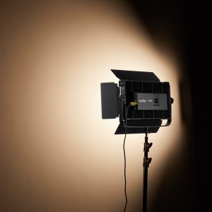 Godox P200BI Studio LED-valopaneeli, joka on asennettu jalustalle, jossa on lato-ovet, heittää fokusoidun säteen beigeen seinään, tuottaen kirkkaan pisteen, jota ympäröivät lempeät varjot.