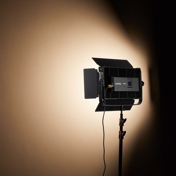 Godox P200BI Studio LED-valopaneeli, joka on asennettu jalustalle, jossa on lato-ovet, heittää fokusoidun säteen beigeen seinään, tuottaen kirkkaan pisteen, jota ympäröivät lempeät varjot.