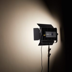 Kolmijalkaiseen jalustaan asennettu Godox P200BI Studio LED-valopaneeli on kytketty päälle, ja se heijastaa kirkkaan, fokusoidun valonsäteen tavalliselle beigelle seinälle luoden pehmeän varjostuksen valaistun alueen ympärille.