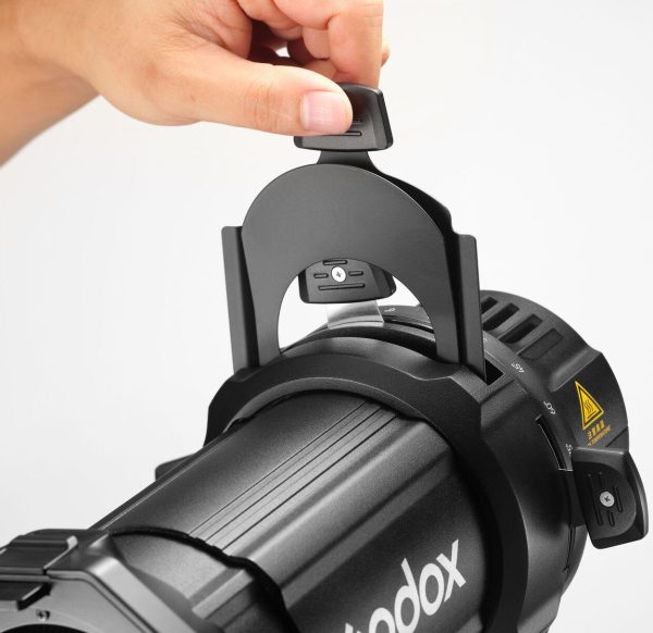 Käsi säätää Godox Spotlight Attachment MLP26K:ta ML30/ML60-studiovaloille, joka on asennettu valon päälle valkoista taustaa vasten.