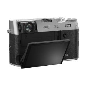 fuji_x100vi_hopea_01 Fujifilm X100VI -kompaktikamera, hopea näkyy takaa sen hopea ja musta runko. LCD-näyttö on käännetty ulos ja kallistettu alaspäin, jolloin kameran hallintalaitteet ja kuvioitu kahva paljastuvat.