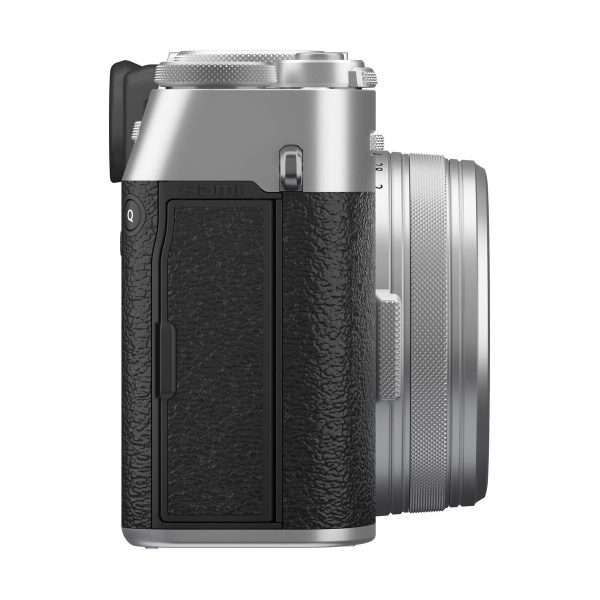 fuji_x100vi_hopea_03 Fujifilm X100VI -kompaktikamera, hopea näkyy sivulta, ja siinä on hopean ja mustan värinen viimeistely, kuvioitu kahva, näkyvä objektiivi ja etsin sekä erilaisia painikkeita ja portteja sivulla.