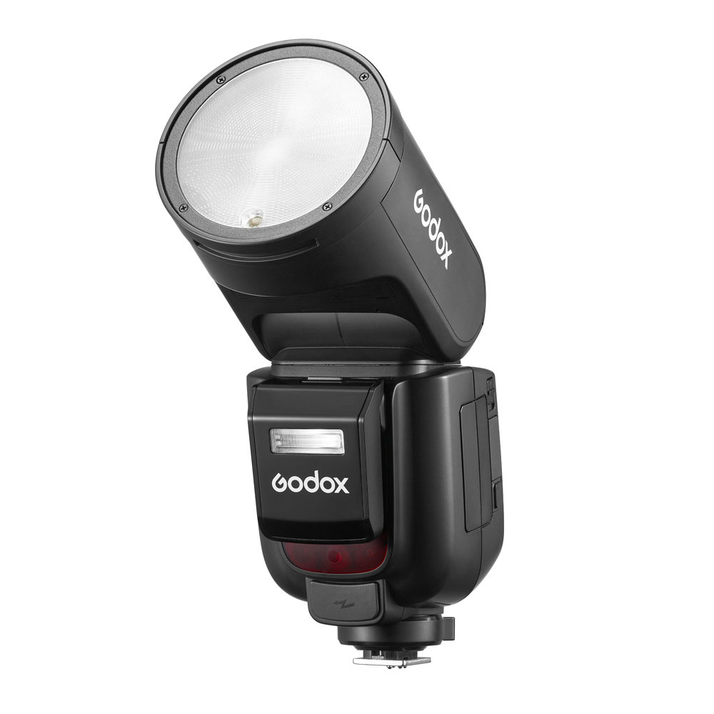 Musta Godox V1 Pro -salama Canon-kameroille, jossa on pyöreä pää, on kuvassa ylöspäin suunnattuna. Godoxin logo näkyy rungossa ja päässä, ja alareunassa näkyy kiinnityskannatin.