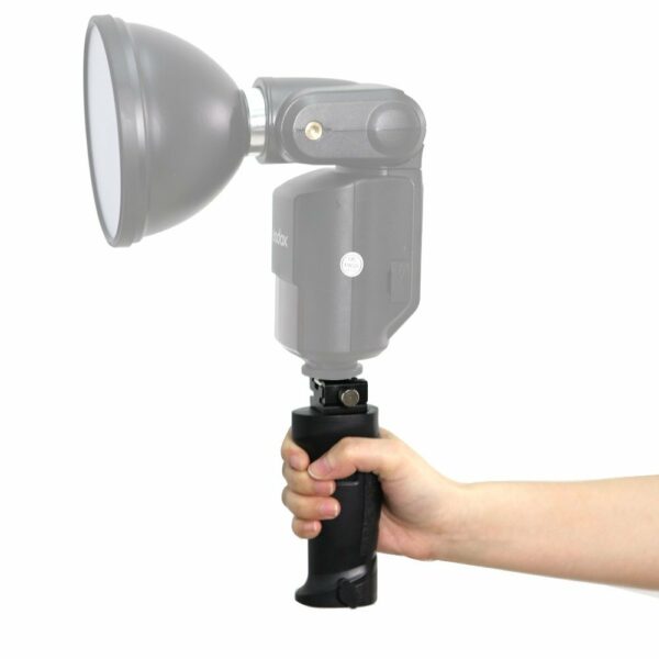 Käsi pitelee Godox Witstro Handgrip -käsikahvaa, jonka päälle on asennettu puoliksi läpinäkyvä salamalaite valkoista taustaa vasten.