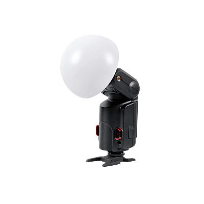 Godox Witstro Diffusor Ball (ilman metalliosaa), suuri valkoinen diffuusiokupu, on kuvassa kiinnitettynä kameran salamalaitteeseen, jossa on musta runko ja punaiset aksentit, ja joka seisoo tasaisella kiinnitysalustalla valkoista taustaa vasten.