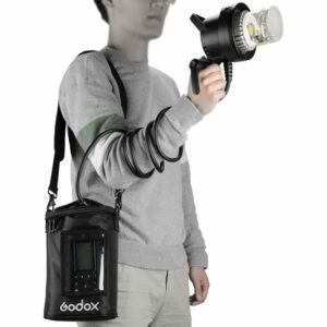 1560261309_067 The person is wearing a grey sweater and light-coloured trousers, and is holding a hand-held salamander connected by a coiled cable to a Godox AD600Pro power supply hanging over his shoulder in a black Godox PB-600P Portable Bag.