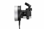Godox R1200 -rengassalamapää AD1200Pro:lle on kuvassa mustana, ja sen etupuolelle on asennettu suuri rengassalama, sivulta katsottuna valkoista taustaa vasten. Rengassalamaan on liitetty virtajohto.