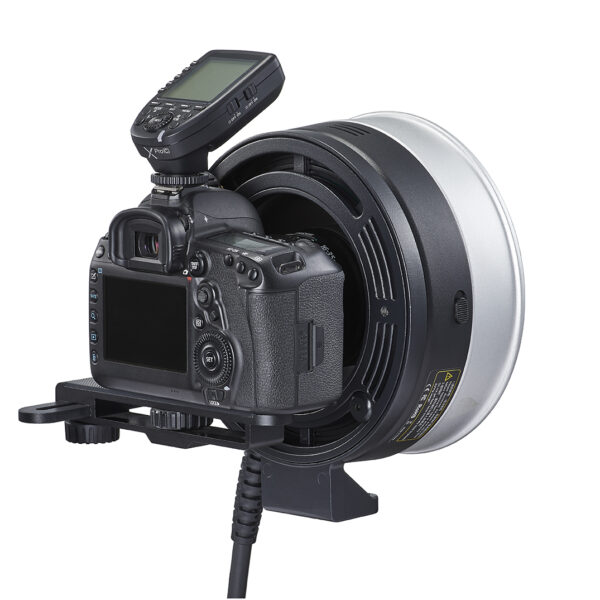 Digitaalinen DSLR-kamera on kiinnitetty Godox FLB-90 Quick Rotating Camera Bracket Kit for R1200 -laitteeseen, johon on kiinnitetty hopeanvärinen ja musta rengassalama ja langaton laukaisulähetin kameran kuumakenkään.