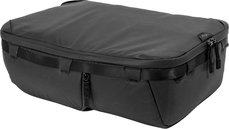 Peak Design Camera Cube V2 (Large) on musta, suorakaiteen muotoinen matkalaukku, jossa on vetoketju, vahvistetut reunat ja säädettävät hihnat, ja se on kuvattu vaalealla taustalla.