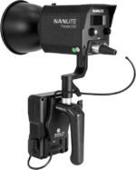 The NANLITE V Mount battery handle with 4-pin XLR connector is attached to the Nanlite Forza 150 LED studio light with the handle, control panel and visible power cables in the side view.