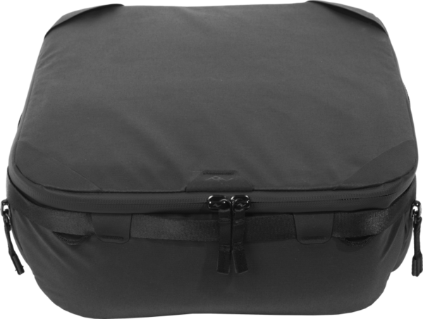 Peak Design Camera Cube V2 (Medium) on musta, pehmeäpintainen, suorakaiteen muotoinen järjestäjä, jossa on kaksinkertainen vetoketju ja sivukahvat, ja joka on suunniteltu kameravarusteiden ja tarvikkeiden siistiin säilytykseen matkatavaroiden sisällä.