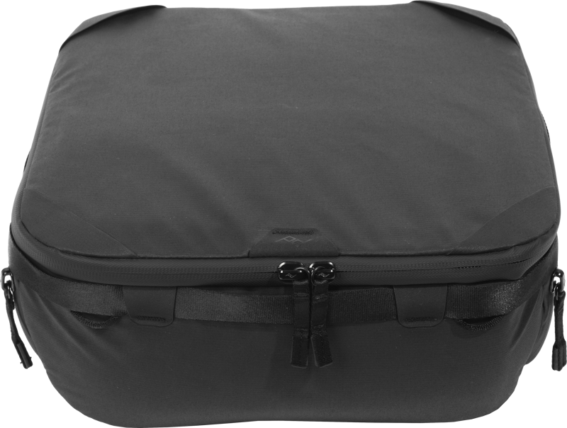 Peak Design Camera Cube V2 (Medium) on musta, pehmeäpintainen, suorakaiteen muotoinen järjestäjä, jossa on kaksinkertainen vetoketju ja sivukahvat, ja joka on suunniteltu kameravarusteiden ja tarvikkeiden siistiin säilytykseen matkatavaroiden sisällä.
